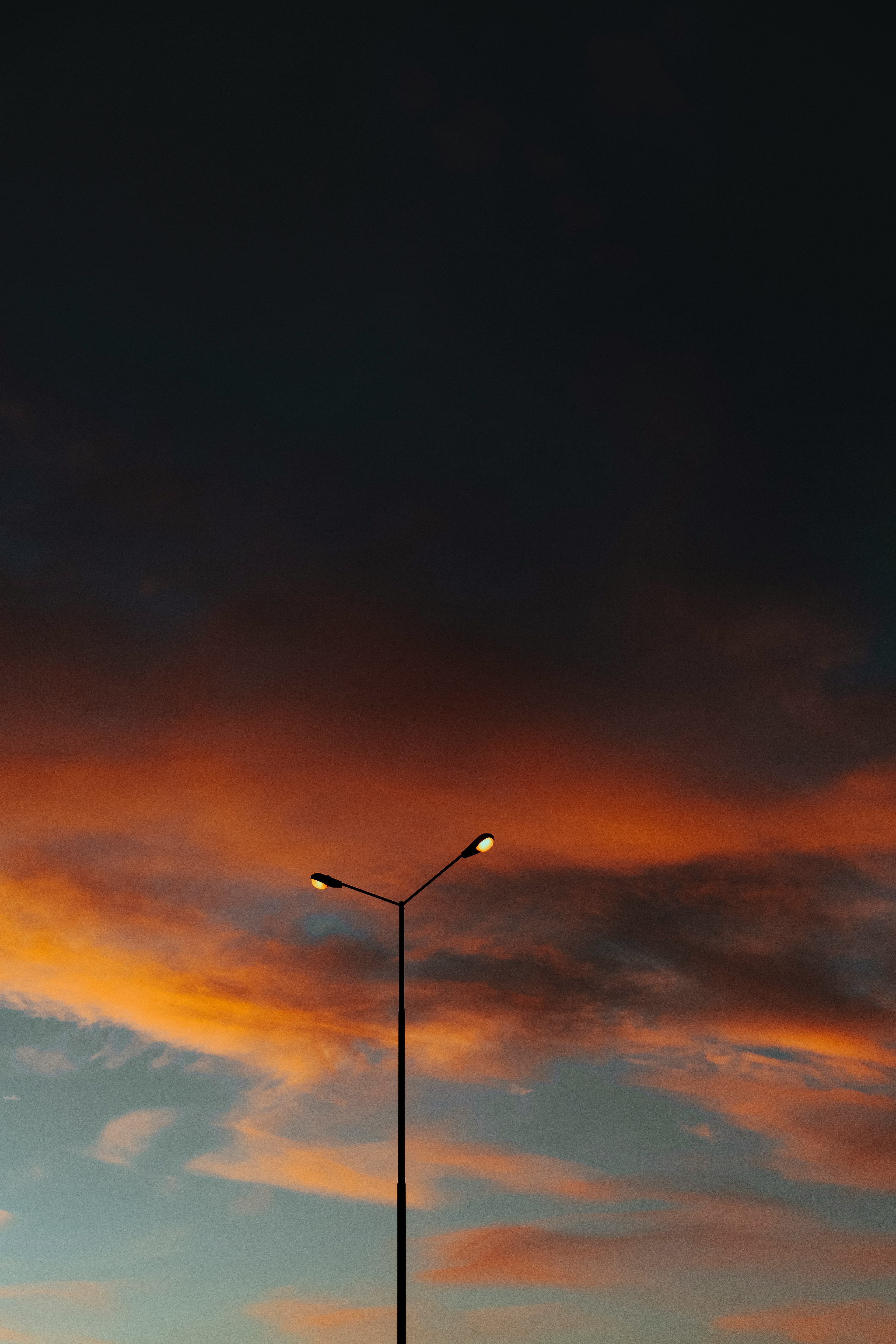 black street light under orange and blue sky